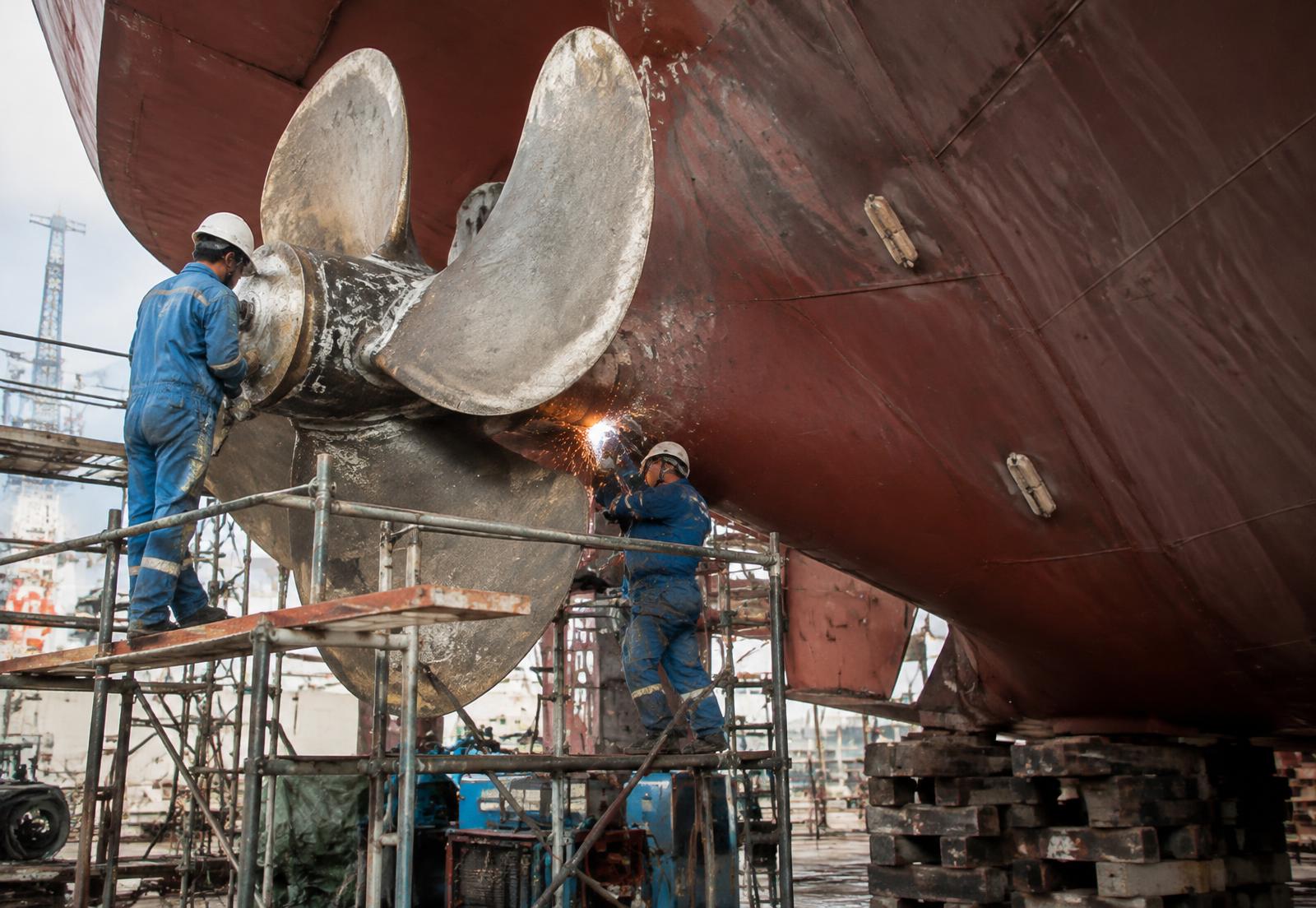 Engineers repairing a ship propeller in dry dock